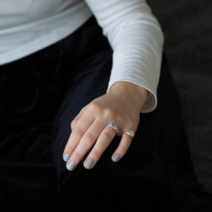 A caucasian female resting her hands on her leg, wearing Cloud Mist, a medium to light grey silvery nail polish