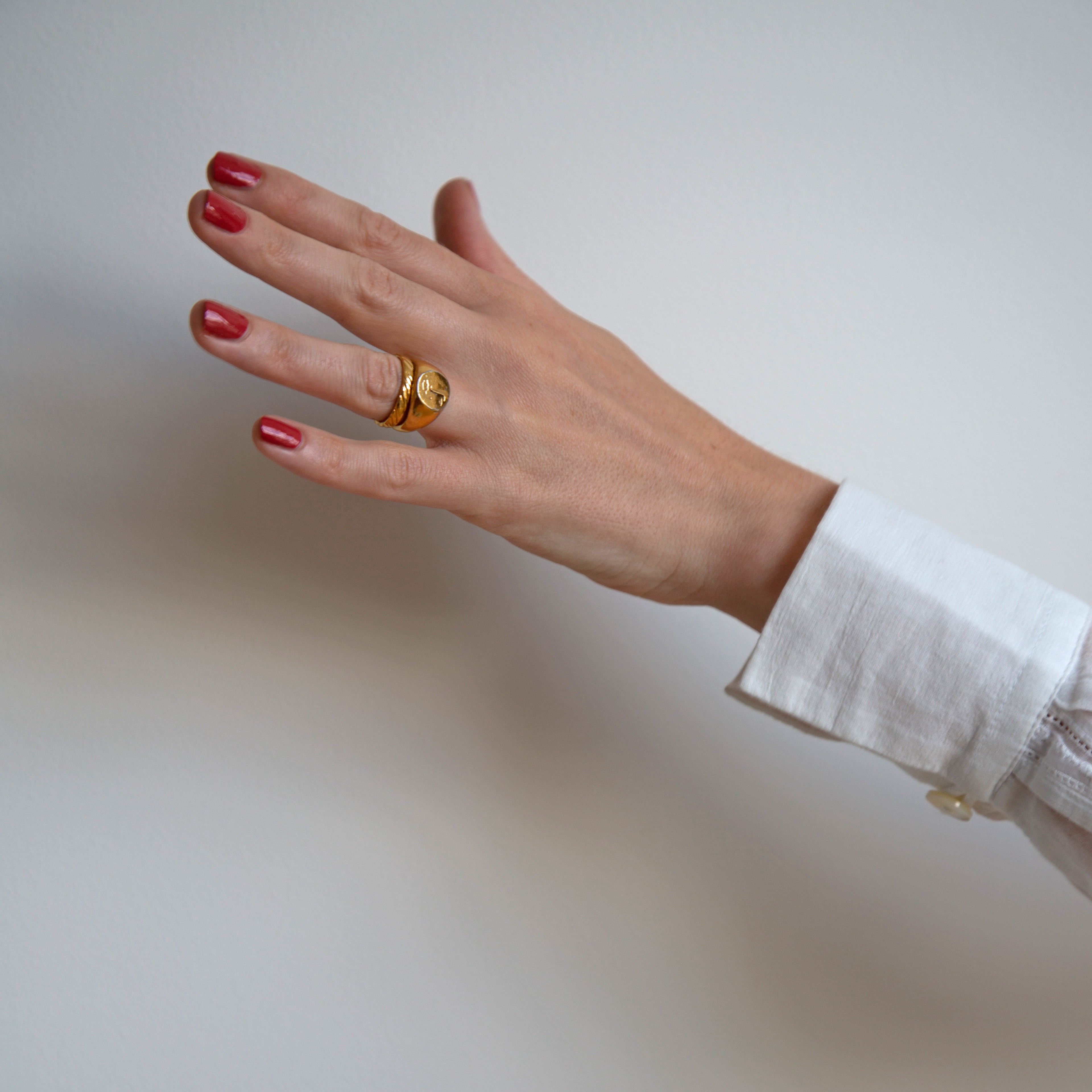 A female hand stretched out against a white backdrop wearing Tuscan Summer, a burnt orange red shade of nail polish by Paint Nail Lacquer