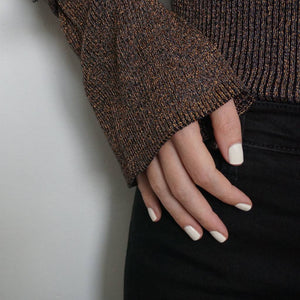 A female hand on hip wearing Coconut Cream paint nail polish a creamy white gloss shade