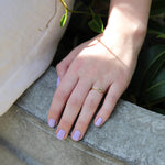A female resting her hand on concrete, wearing Lilac Fizz a light purple shade of nail polish