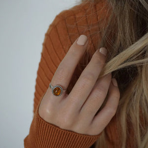 A female in a brown sweater clutching a handful of her hair, wearing Paint Naked nail polish a light nude colour