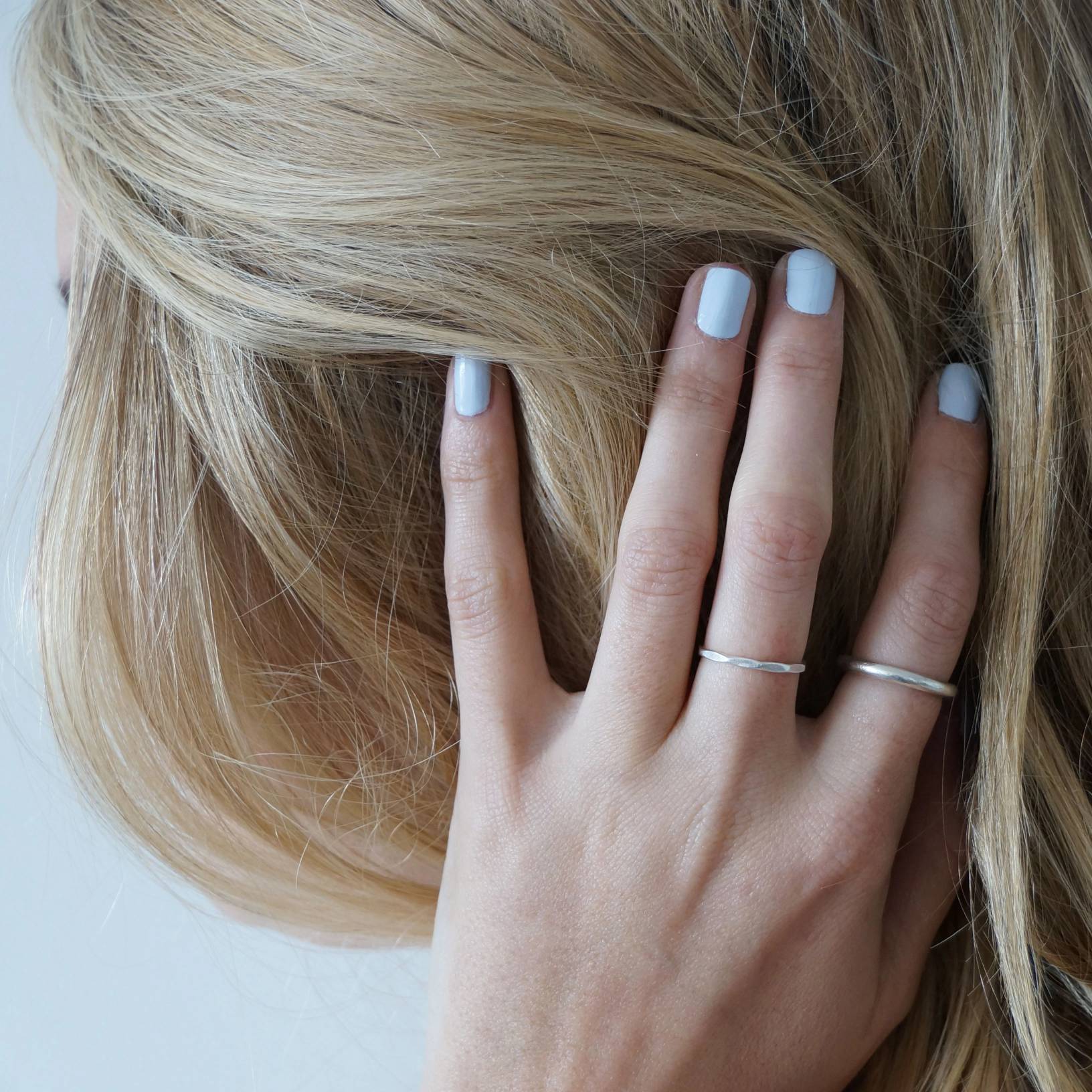 A female with her hand clutching her hair wearing Pale Glacier a light baby blue colour by Paint Nail Lacquer