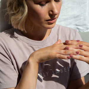 Molly Smyth clutching her hands together, wearing Sangria a medium to dark pink colour of nail polish by Paint Nail Lacquer