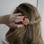 A female clutching the back of her hairclip, wearing Scarlet Venom a dark red nail polish by Paint Nail Lacquer