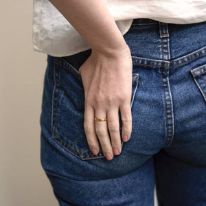 A female with her thumb in the back pocket of her jeans, exposing her hand resting on her backside wearing Tribal Blossom a creamy orange brown nail polish.