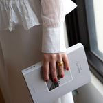 A female holding a white book about London, wearing Tuscan Summer a burnt orange shade of nail polish and a gold ring.