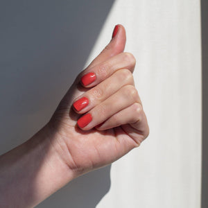 A closed female hand in the sunlight wearing Tuscan Summer, a burnt red orange colour of nail polish
